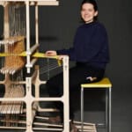 Frau arbeitet an einem Holz-Webstuhl, zeigt Handarbeit und Handwerkskunst.