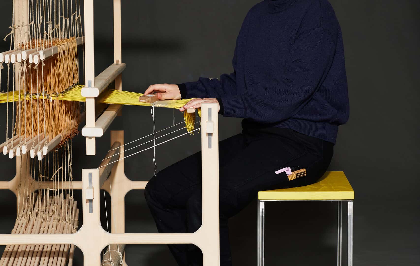Frau arbeitet an einem Holz-Webstuhl, zeigt Handarbeit und Handwerkskunst.